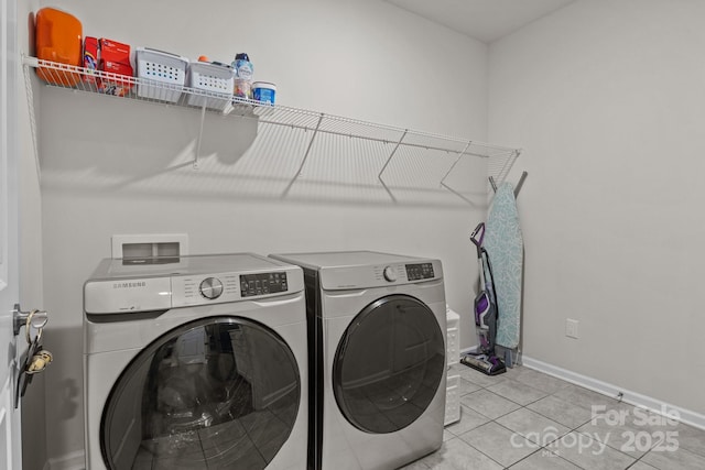 washroom with washer and dryer, baseboards, light tile patterned flooring, and laundry area