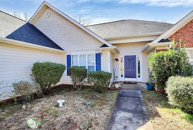 view of exterior entry with roof with shingles