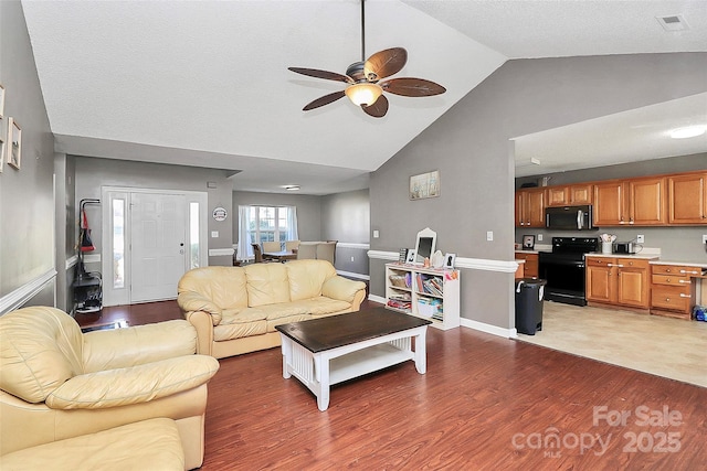 living room featuring a ceiling fan, visible vents, baseboards, lofted ceiling, and dark wood-type flooring