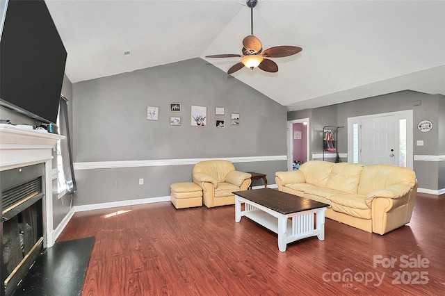 living room with a glass covered fireplace, wood finished floors, baseboards, ceiling fan, and vaulted ceiling