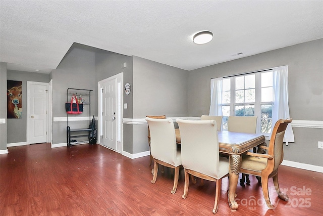 dining space with visible vents, a textured ceiling, baseboards, and wood finished floors