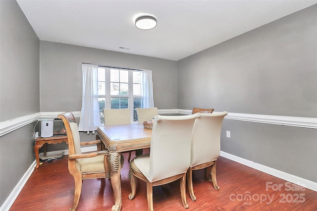 dining room with visible vents, baseboards, and wood finished floors