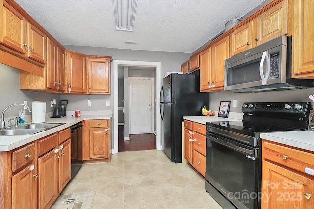 kitchen featuring a sink, visible vents, black appliances, and light countertops