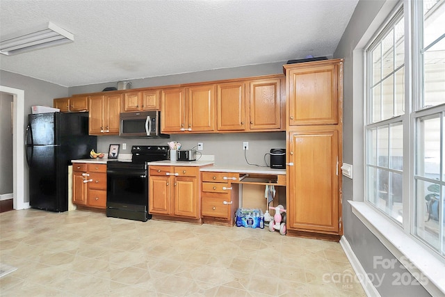 kitchen featuring black appliances, baseboards, light countertops, brown cabinetry, and a textured ceiling