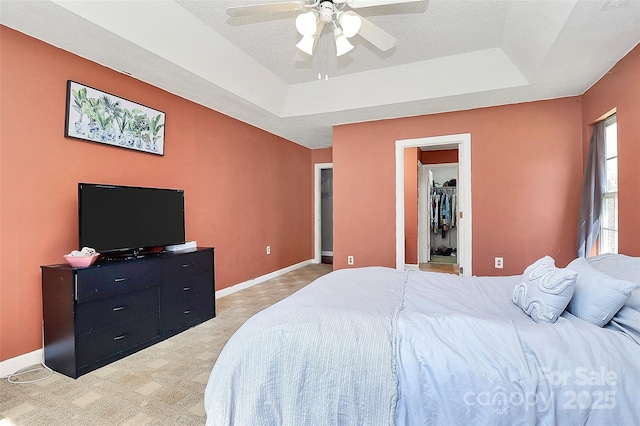 bedroom featuring light carpet, a raised ceiling, and baseboards