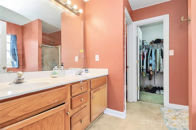 full bath with a sink, a spacious closet, double vanity, and a shower stall