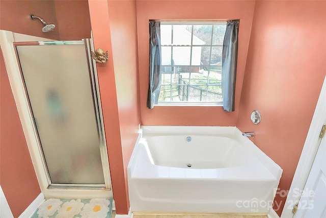 bathroom featuring a stall shower and a bath