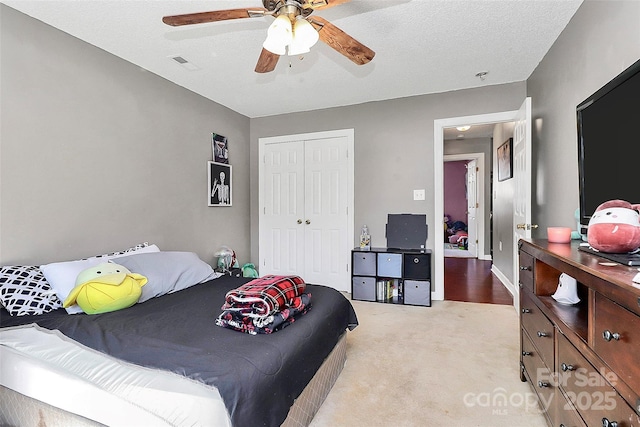 bedroom with a closet, visible vents, light colored carpet, and a ceiling fan