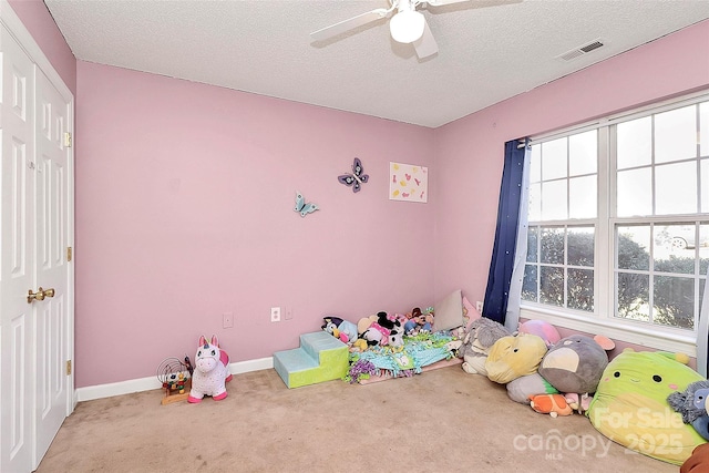 rec room with a ceiling fan, baseboards, visible vents, carpet floors, and a textured ceiling