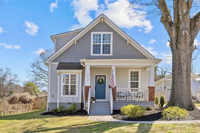 view of front of house featuring a porch, fence, and a front yard