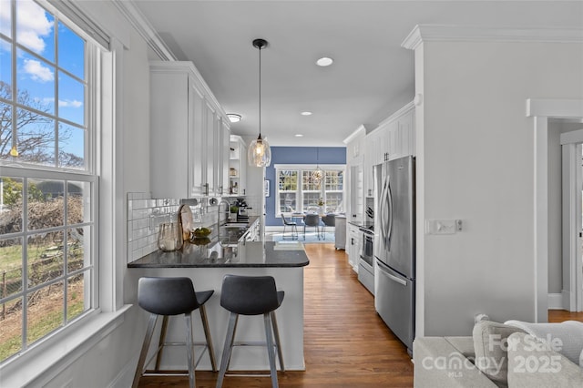 kitchen with backsplash, dark countertops, white cabinets, and freestanding refrigerator