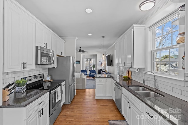 kitchen with a sink, open floor plan, white cabinetry, and stainless steel appliances