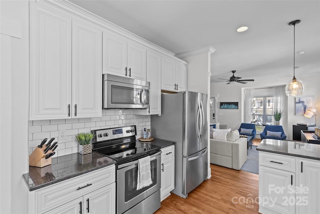 kitchen with backsplash, open floor plan, stainless steel appliances, light wood-style floors, and white cabinetry