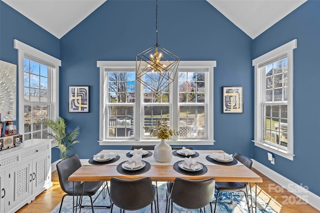 dining room with a wealth of natural light, a notable chandelier, wood finished floors, and vaulted ceiling