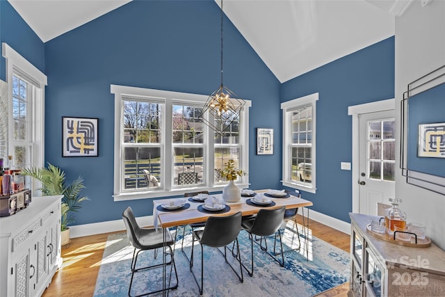 dining space featuring a chandelier, baseboards, light wood-style flooring, and vaulted ceiling