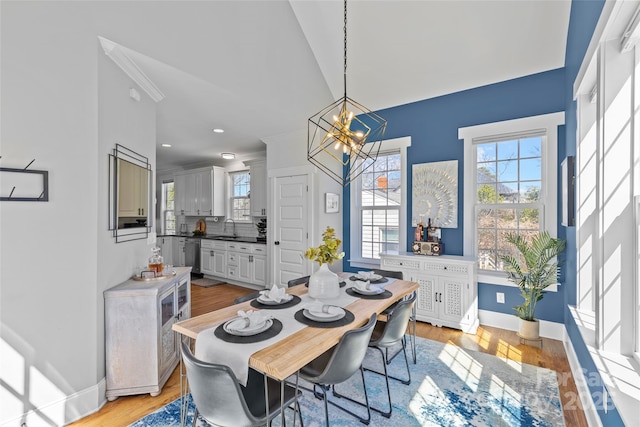 dining space featuring a wealth of natural light, a notable chandelier, light wood-style flooring, and baseboards