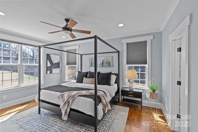 bedroom with baseboards, multiple windows, wood finished floors, and crown molding