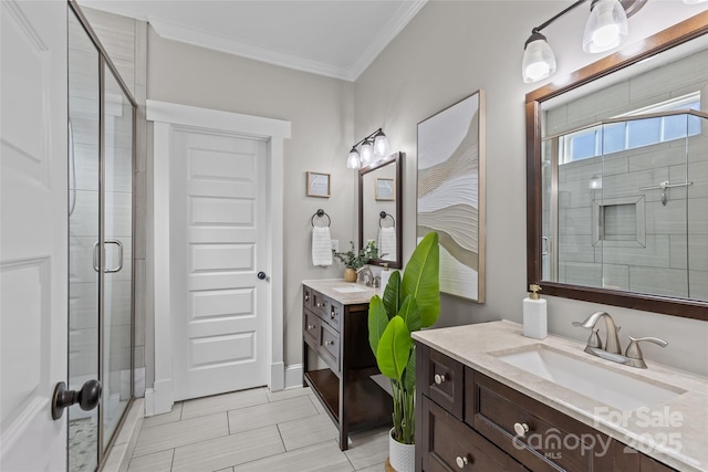 full bath featuring two vanities, a shower stall, crown molding, and a sink