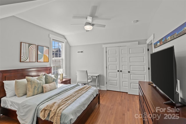 bedroom featuring visible vents, lofted ceiling, a closet, a ceiling fan, and wood-type flooring