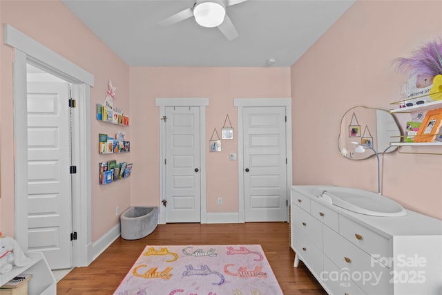 bedroom featuring a ceiling fan, baseboards, and wood finished floors