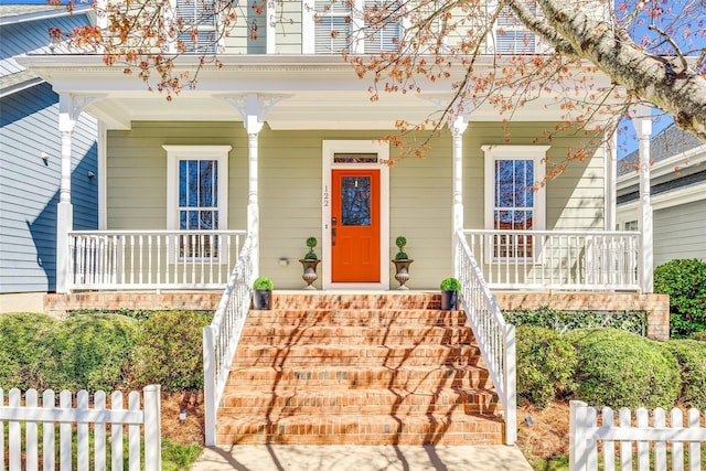 view of front of property with stairway, covered porch, and fence