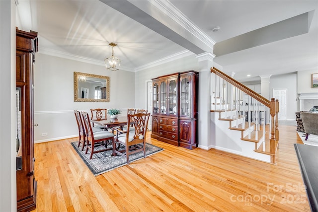 dining space with a notable chandelier, wood finished floors, stairway, crown molding, and ornate columns