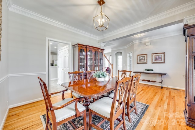 dining area featuring arched walkways, a notable chandelier, light wood-style flooring, and crown molding