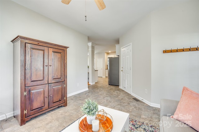 living area featuring visible vents, baseboards, a ceiling fan, and ornate columns