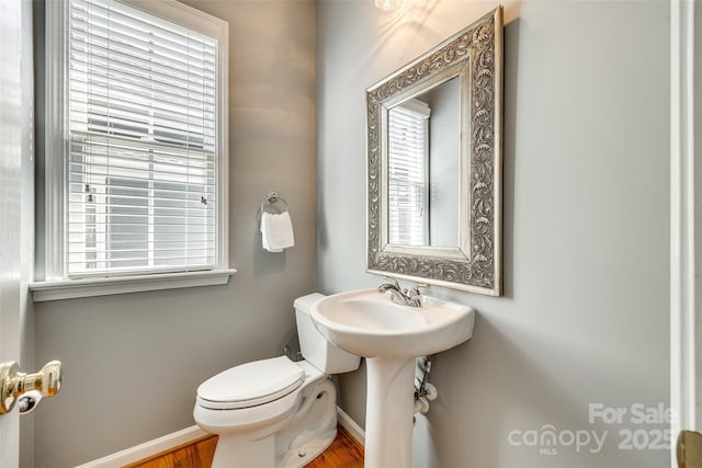 bathroom with toilet, plenty of natural light, and baseboards