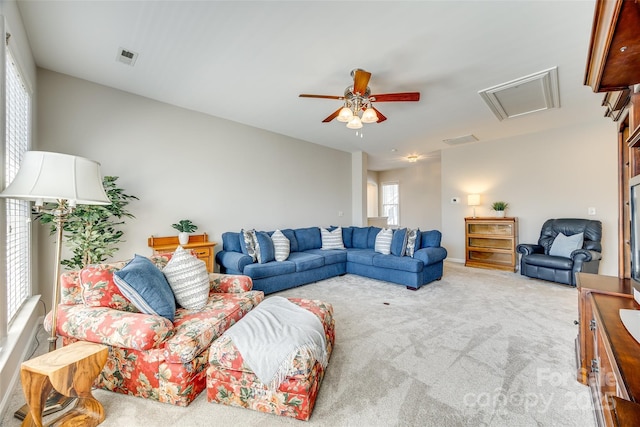 carpeted living room with attic access, a ceiling fan, and visible vents