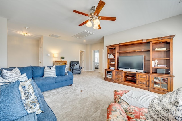 carpeted living room featuring attic access, baseboards, and ceiling fan