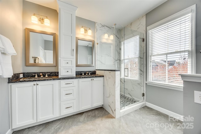 full bathroom with a healthy amount of sunlight, a marble finish shower, and a sink