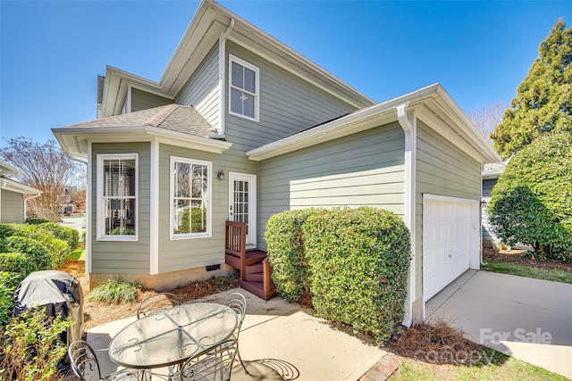 back of house featuring crawl space, driveway, an attached garage, and a shingled roof