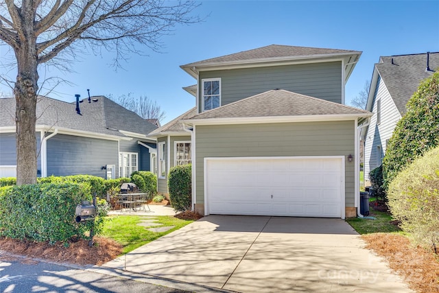 traditional home featuring a patio area, concrete driveway, a garage, and roof with shingles