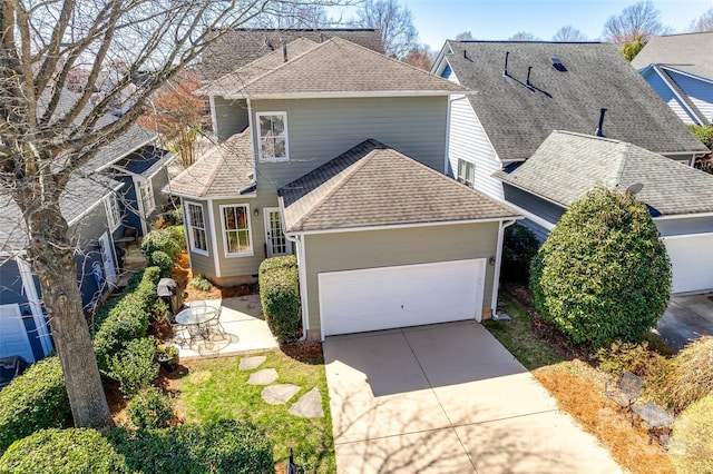 traditional-style house featuring driveway, a shingled roof, a garage, and a patio