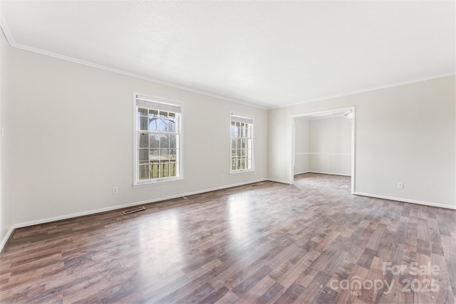 spare room featuring visible vents, wood finished floors, baseboards, and ornamental molding