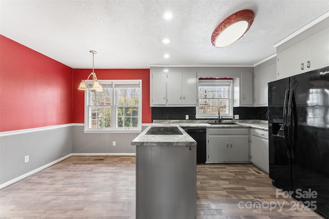 kitchen with a wainscoted wall, plenty of natural light, black appliances, and wood finished floors