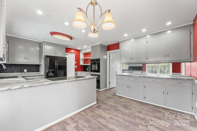 kitchen with backsplash, a peninsula, light wood-style floors, black appliances, and a sink