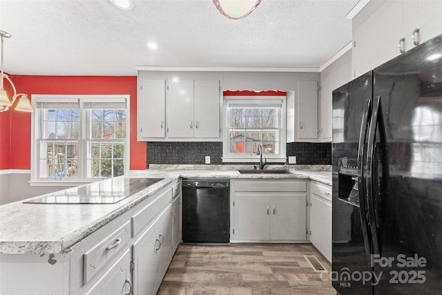 kitchen featuring decorative backsplash, black appliances, light countertops, and a sink