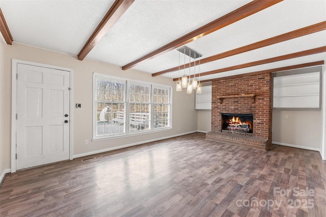 unfurnished living room featuring wood finished floors, visible vents, baseboards, beam ceiling, and a textured ceiling