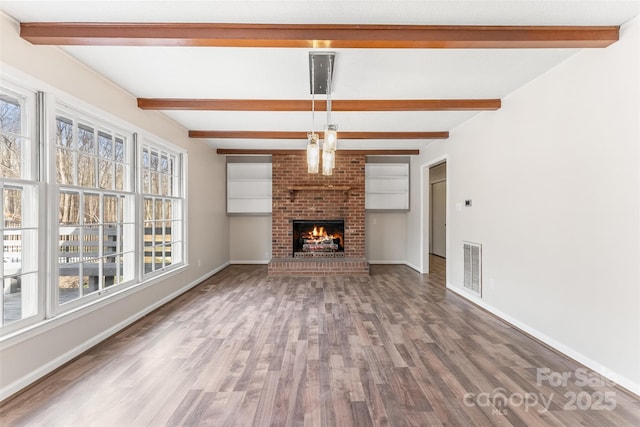 unfurnished living room featuring visible vents, baseboards, and wood finished floors