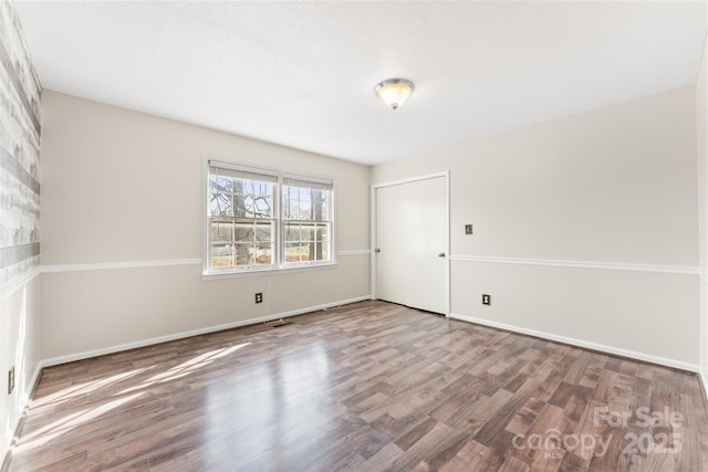 spare room featuring baseboards and wood finished floors