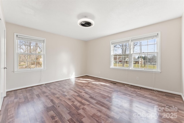 spare room with visible vents, wood finished floors, and baseboards