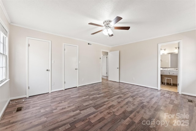 unfurnished bedroom with visible vents, ornamental molding, baseboards, and wood finished floors