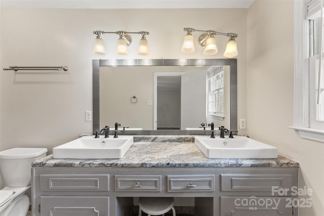 full bathroom with double vanity, toilet, and a sink