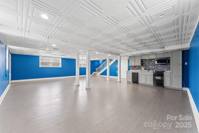 basement featuring baseboards, stairs, wood finished floors, an ornate ceiling, and a sink