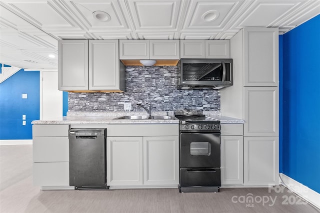 kitchen featuring light stone countertops, baseboards, a sink, black appliances, and backsplash