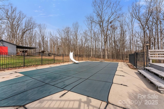 view of swimming pool with a fenced in pool, a water slide, and fence