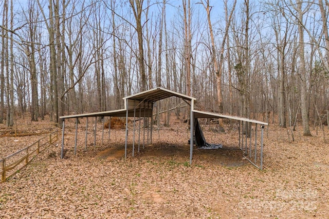 view of outdoor structure with a detached carport and fence