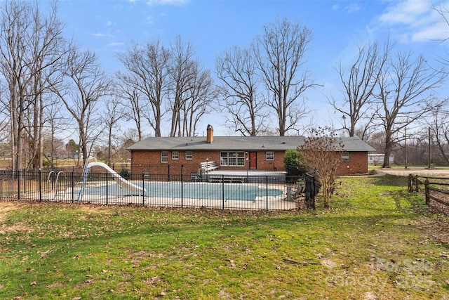 view of pool with a lawn, a patio, fence, a water slide, and a fenced in pool